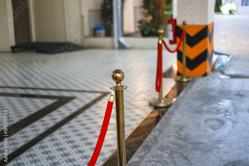 Fotografie Gold stanchion with red velvet rope creates an exclusive barrier at an event entrance
