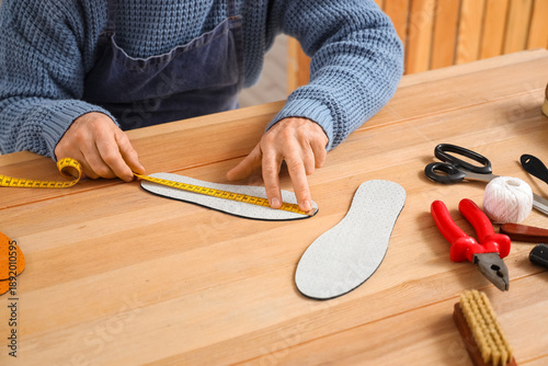 Fotografía Mature male shoemaker measuring insole at table in workshop, closeup