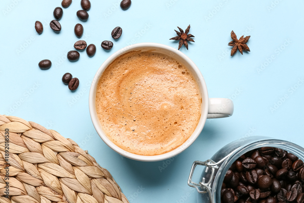 Obraz premium Cup of hot espresso and coffee beans on blue background
