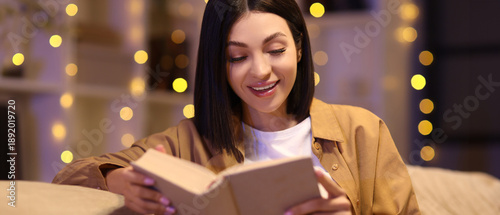 Happy young woman reading b...