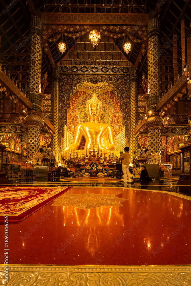 Obraz premium Chiang Mai, Thailand - January,08, 2026:Golden Shrine of Tranquility: The interior of a magnificent temple shimmers with ornate golden details, a large statue of buddha sits as the focal point