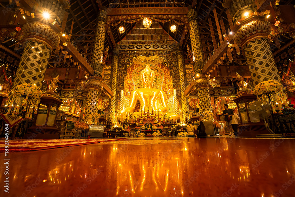 Obraz premium Chiang Mai, Thailand - January,08, 2026:Golden Shrine of Tranquility: The interior of a magnificent temple shimmers with ornate golden details, a large statue of buddha sits as the focal point
