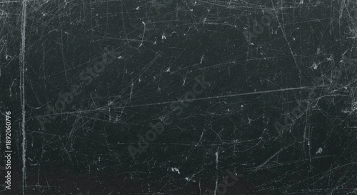 Dark, textured surface with numerous scratches and light imperfections.