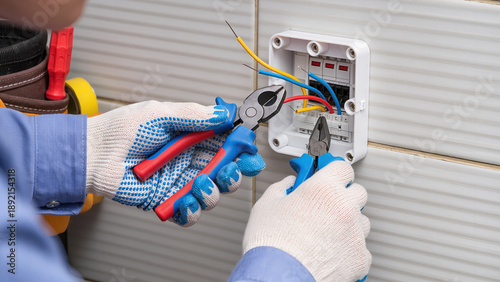 electrician working with electrical wires, Industrial service, Organized wiring, Electrician is fixing the panel, Person handles the electrical parts, Electrician performs a panel repair, 