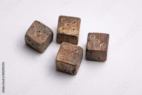 Close-up of Roman-era dice carved from bone, featuring worn edges and hand-carved pips. These ancient gaming pieces reflect leisure and gambling practices in the Roman Empire.