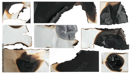 Several torn and partially burnt black and white paper pieces scattered against a black backdrop