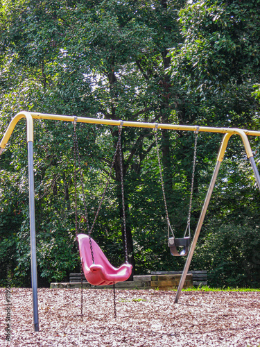 An empty  pink swing seat with a lush garden in the background