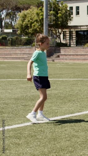 Vertical video: Starting with ball at foot child in mint tee tapping it on white line looking right
