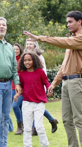 Vertical video: Family walking across lawn as tan-shirt man stepping forward holding hands together