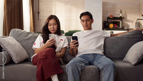 Fotografía Sad ignore couple sit couch at home using smartphone