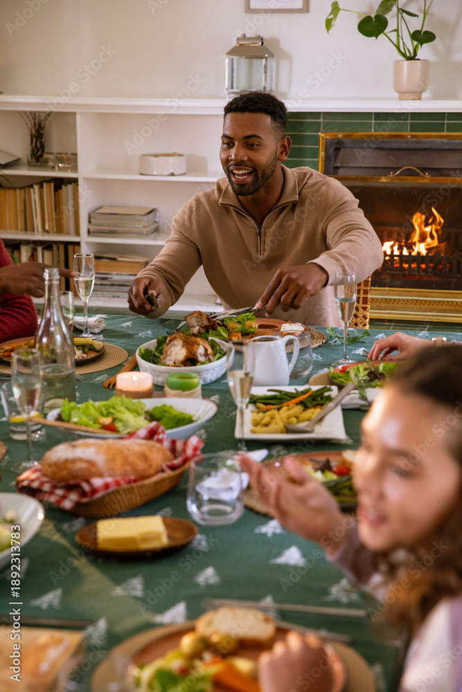 Obraz premium Diverse friends gathering around holiday-patterned table carving roasted chicken
