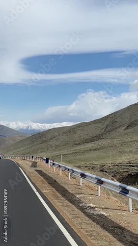 Car driving on a scenic mountain road with snow-capped peaks in the background under a blue sky. Armenia, Yerevan 15.04.2023