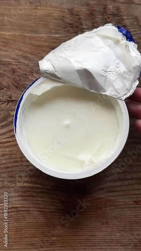 Open Greek yogurt on wooden background, top view