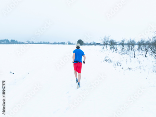 A man jogging on a snow path alone thus improving his health