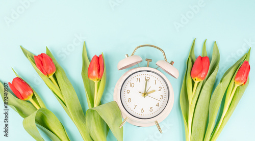 Switch to daylight saving time in spring, summertime changeover, alarm clock with red tulip flowers