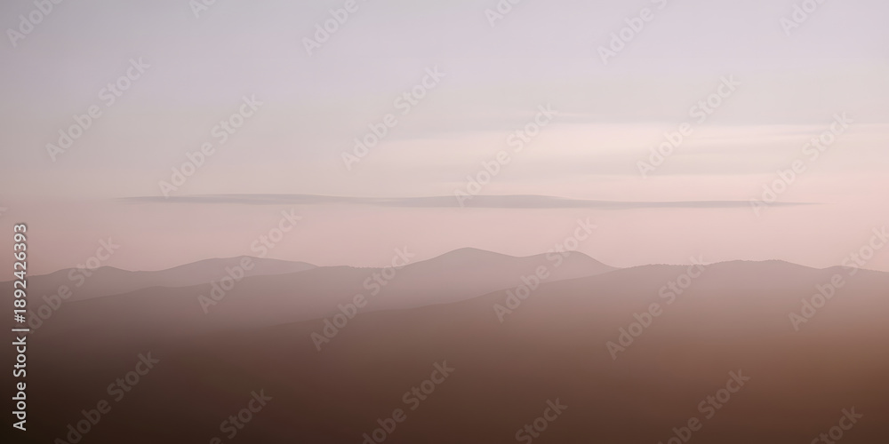 Obraz premium Ethereal layers of mountains shrouded in fog at dawn