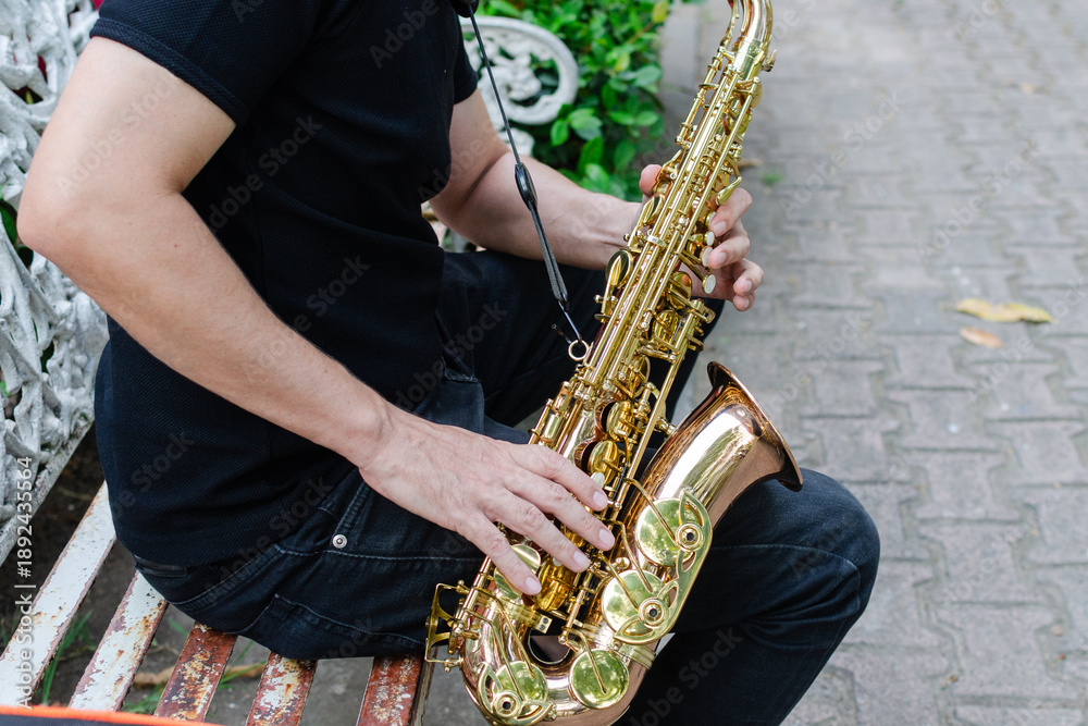 Naklejka premium Authentic Musician Playing Golden Saxophone Instrument Outdoors on a Rustic Bench