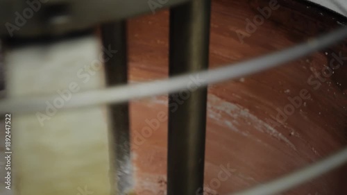 Close-up inside copper mixer slowly stirring thickening, firmer chocolate mixture in chocolate factory.