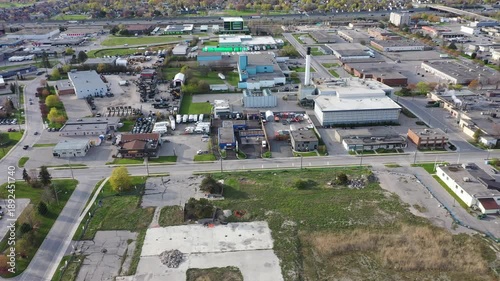 Aerial view flying over a commercial and industrial district with warehouses, factories, and commercial buildings under a clear sky. In ajax ontario canada