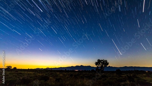A meteor streaks across the night sky over a serene landscape at dusk.