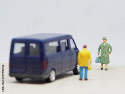 Mini toy of action figure at outdoor with blurred background. Miniature photography concept design. Minifigure of young man character as a passengers with private car and driver.