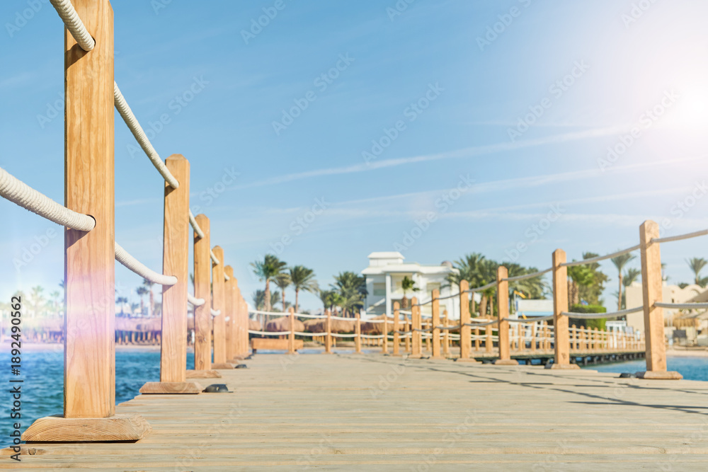 Fototapeta premium Wooden pier on sea stretching into distance beyond horizon on sunny summer day. Vacation and Travel Concept.