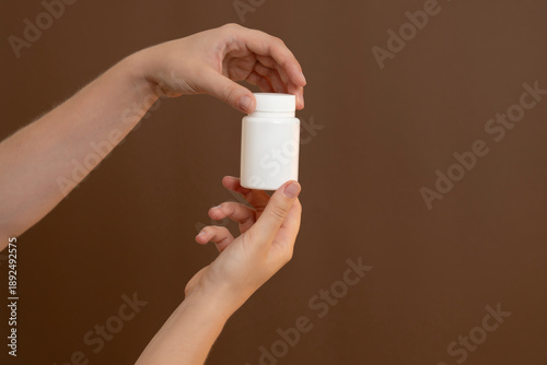 Hands holding white pill bottle for medication and health