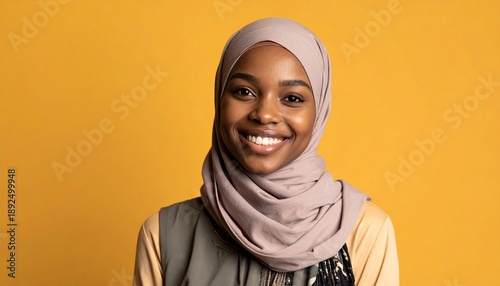 Beautiful young Muslim woman with a warm smile, wearing a stylish hijab and festive attire, against a vibrant yellow backdrop, perfect for diverse cultural and celebratory themes