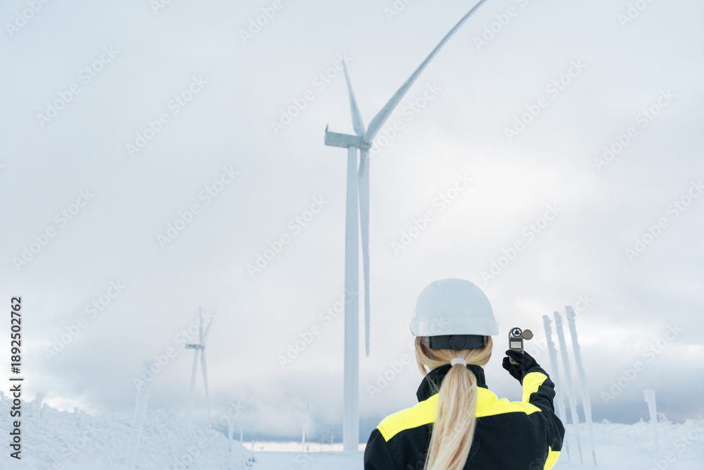 custom made wallpaper toronto digitalWoman engineer standing in large field energy windmills and using digital weather station to measure the wind speed. Winter arctic industrial Wind turbine station.