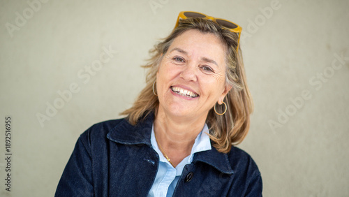Happy senior woman smiling confidently in front of neutral wall