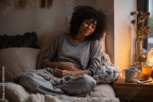 Black woman in bed with menstrual cramps and abdominal pain in a softly lit bedroom