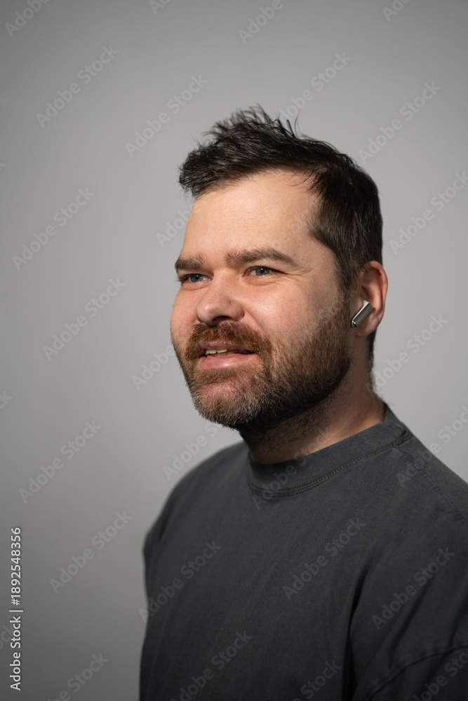 Fototapeta premium Happy bearded man with wireless earbud in his ear