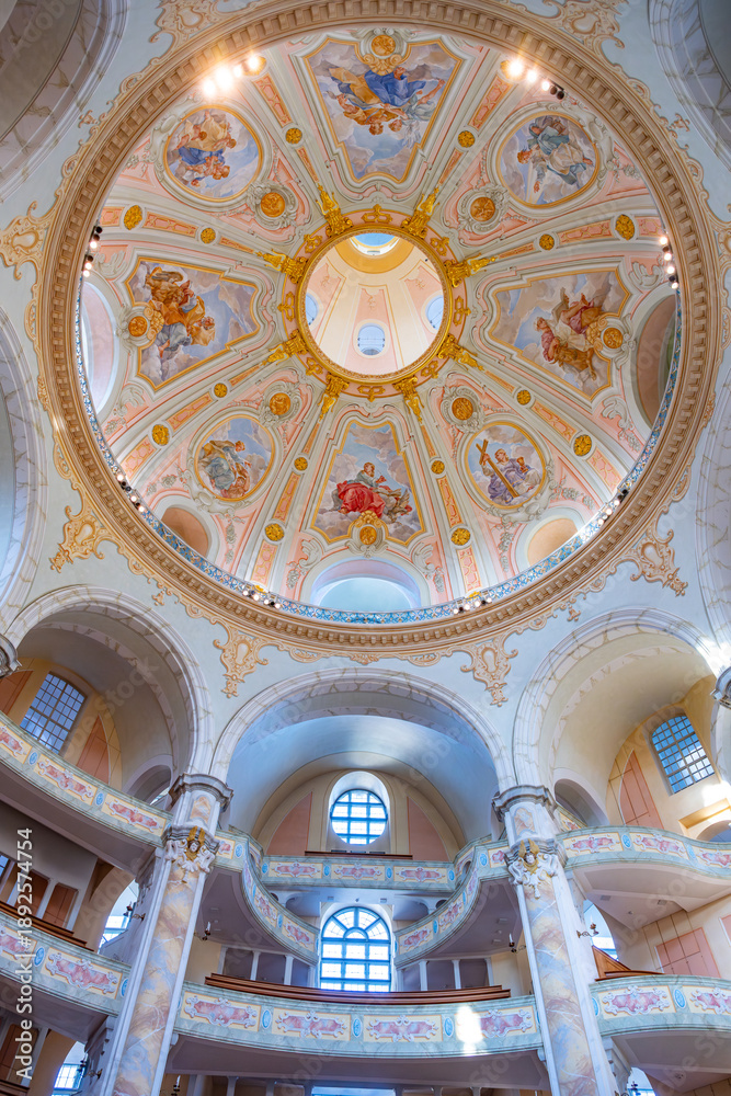 Fototapeta premium Frauenkirche in Dresden shows its dome and detailed design. Visitors admire the artwork on the ceiling while exploring the church's space and structure. Light enters through the windows.