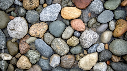 A diverse collection of unpolished natural river stones in various shapes sizes and colors forming a textured ground surface