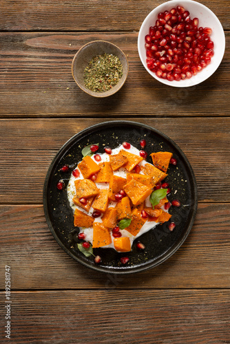 Plate of roasted butternut pumpkin pieces wooden surface