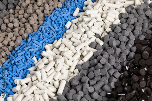 Фотография A high-angle photo shows distinct diagonal rows of nano-sized industrial catalyst pellets in various shapes and colors, including dark gray, brown, light blue, and white
