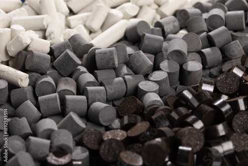 Photography A high-angle photo shows distinct diagonal rows of nano-sized industrial catalyst pellets in various shapes and colors, including dark gray, brown, light blue, and white