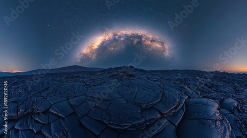 The Milky Way galaxy arching over dark volcanic terrain