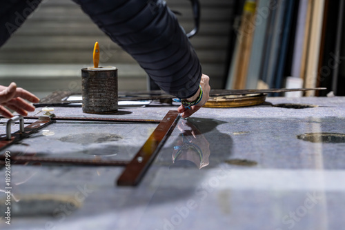 Quadro su tela Miroitier professionnel remplaçant les verres d’une très vieille pendule au bois fortement abîmé, mettant en valeur un travail de restauration artisanale sur un objet patrimonial
