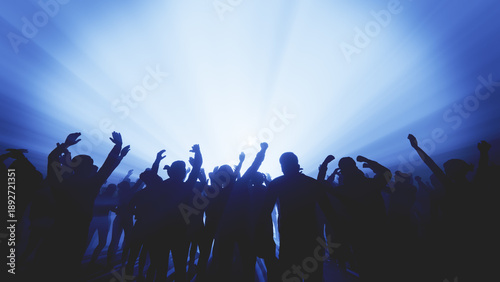 Energetic crowd at a music concert with hands raised towards the stage lights