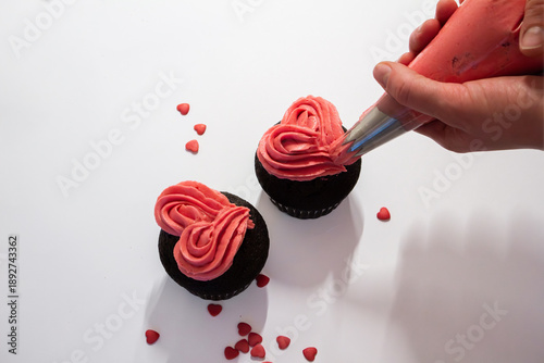 Valokuva Valentine's day cupcakes being decorated with hearts of bright pink frosting