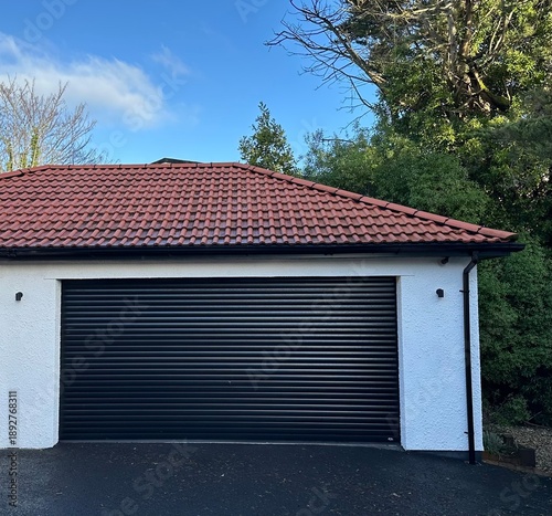 Modern garage outbuilding with red terracotta tiled roof and blue sky