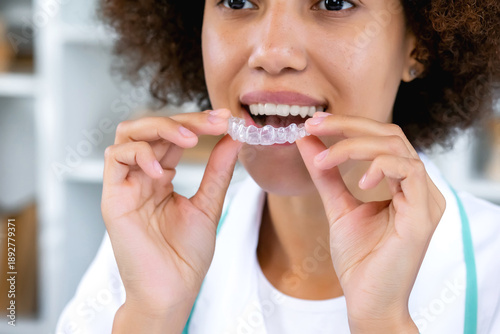 Close-up of orthodontic silicone transparent teeth aligner in female hands putting on. Bracket for teeth whitening.