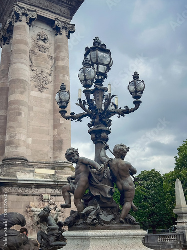 Putti figures and a luxurious street lamp adorn the Alexandre III Bridge. View of the the Pont Alexandre III bridge over the Seine River in spring Paris, France.