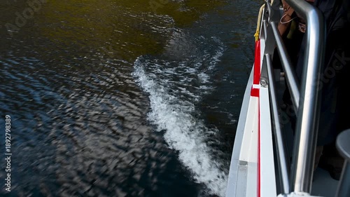 Waves and water wake created by a tourist boat cruising across a lake. Smooth water motion, natural light and peaceful travel atmosphere.