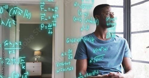 Photos Studying man in blue tee sitting by window, with wireless earbud, viewing cyan e