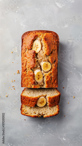 Delicious homemade banana bread loaf with sliced pieces on a textured gray surface