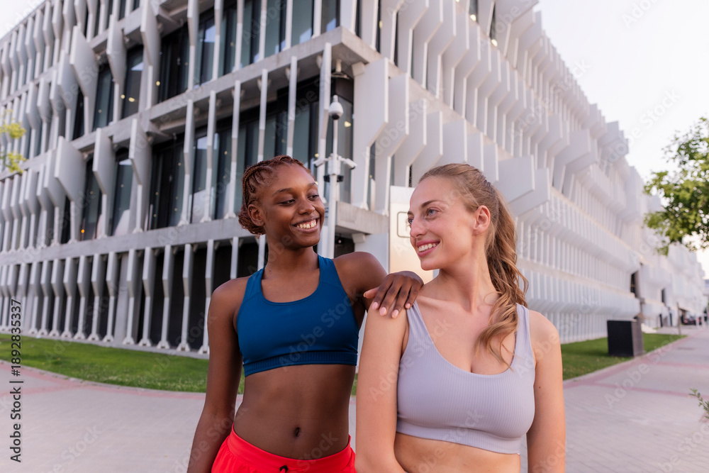 Obraz premium Diverse athletic women friends sharing moment smiling outdoors