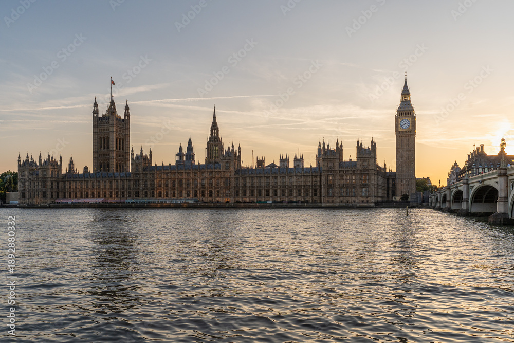 Fototapeta premium London's iconic Big Ben and the Palace of Westminster at sunset, with the Westminster Bridge stretching over the River Thames