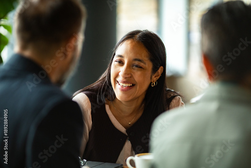 Smiling woman chatting with colleagues at cafe table